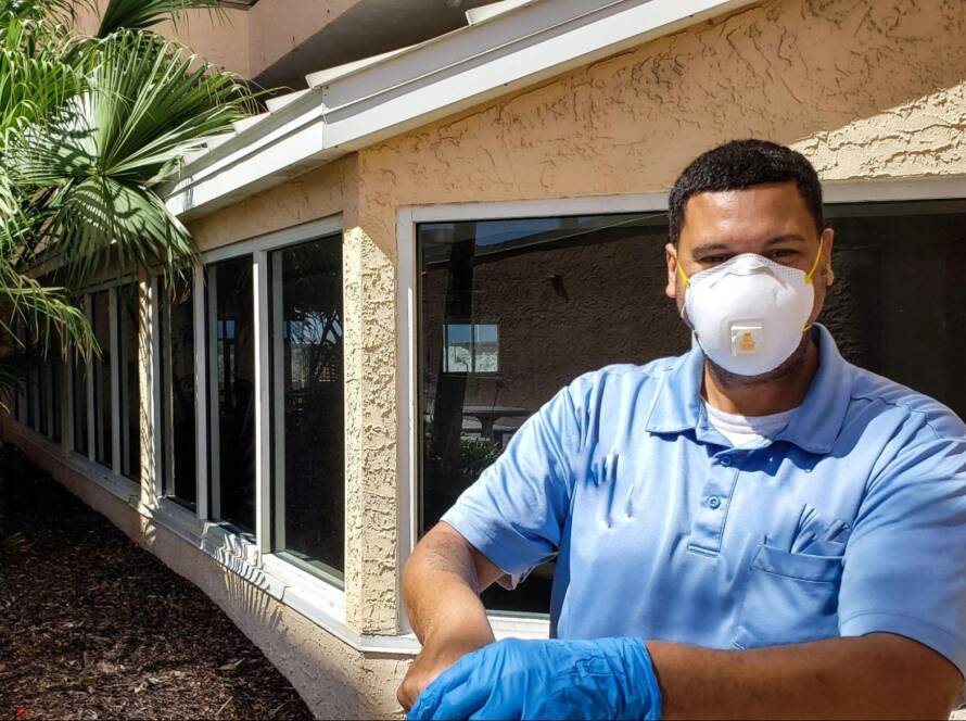 A young pest control crew wearing a face mask prepares to perform termite control.