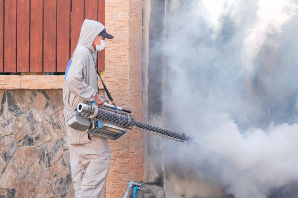 A pest exterminator employee sprays chemicals to deter mosquitoes.