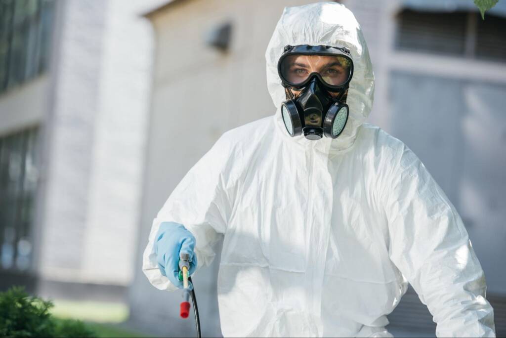 A pest control employee in full protective gear during treatment service.