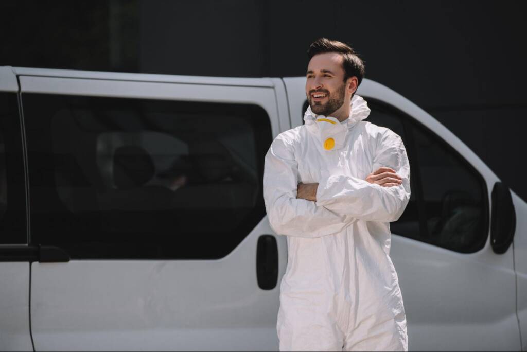 A satisfied pest control worker standing beside a van.